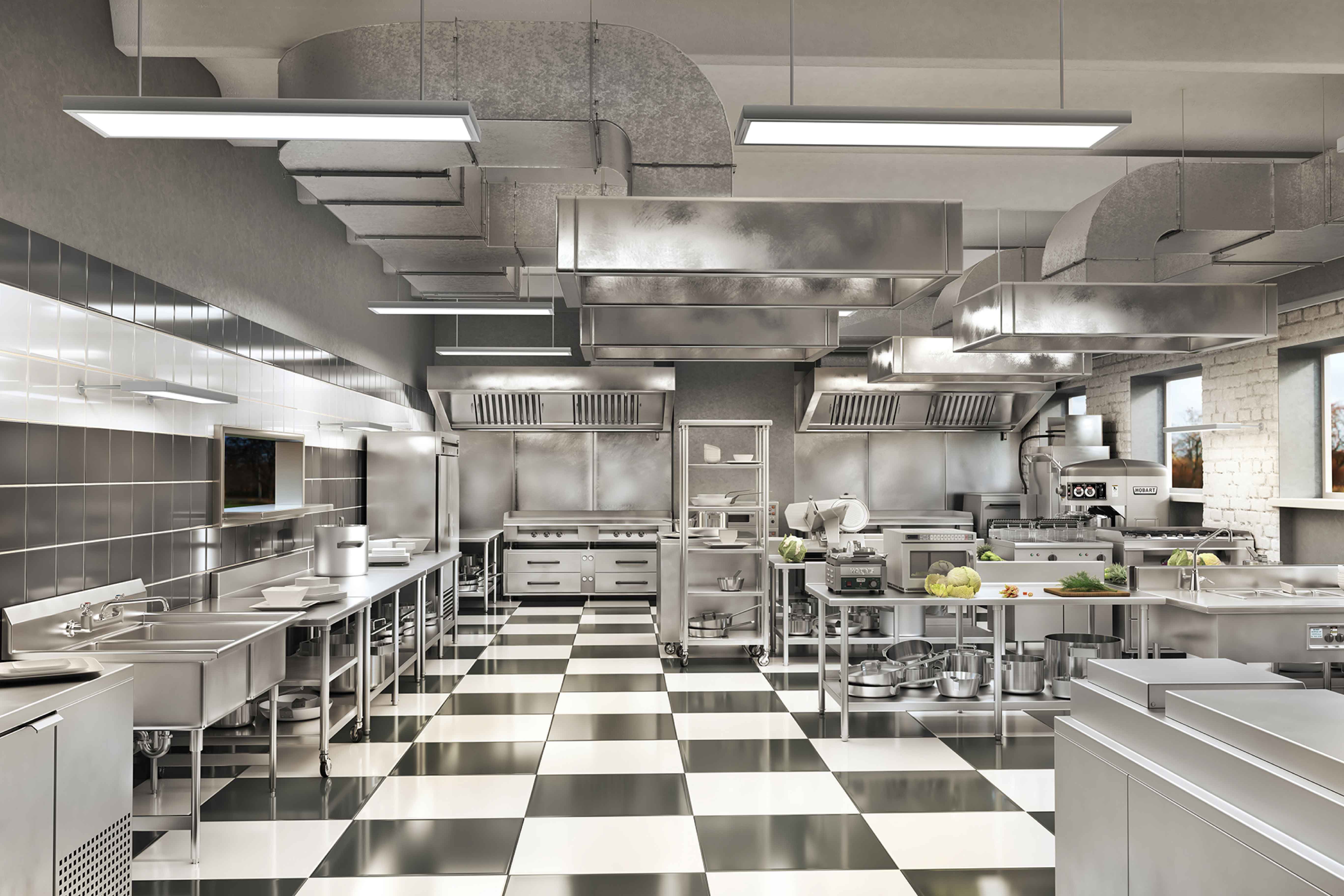 Modern professional hotel kitchen with stainless steel equipment and black and white checkered floor